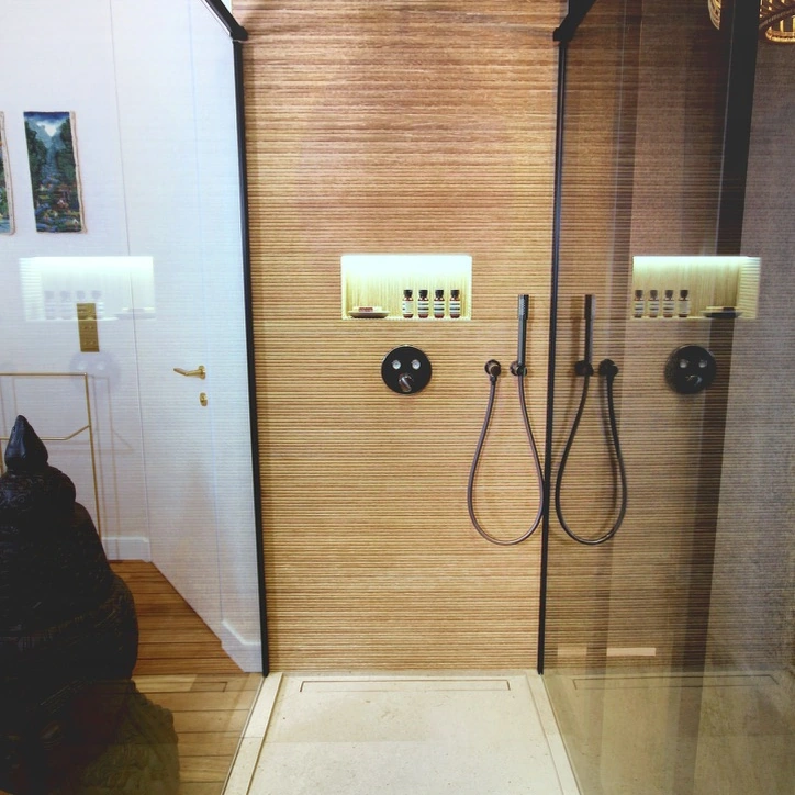 Vue de la grande douche vitrée, de sa robinetterie et de sa niche éclairée.