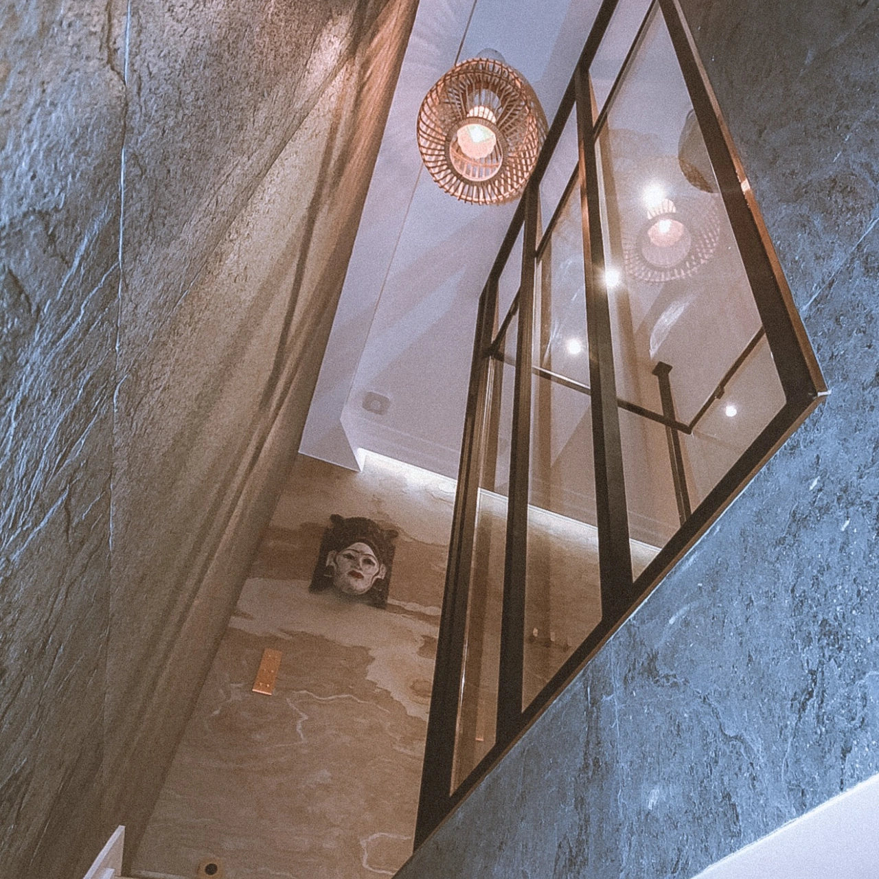 Escalier du duplex bordé de feuilles de pierre naturelle et d’une verrière