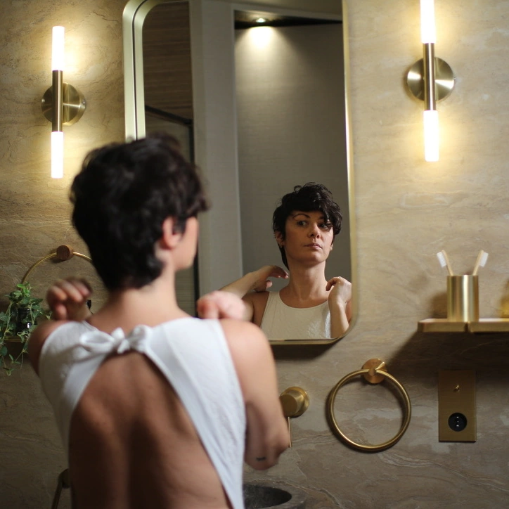 Le mannequin devant le miroir, entre appliques en laiton et murs en pierre naturelle.