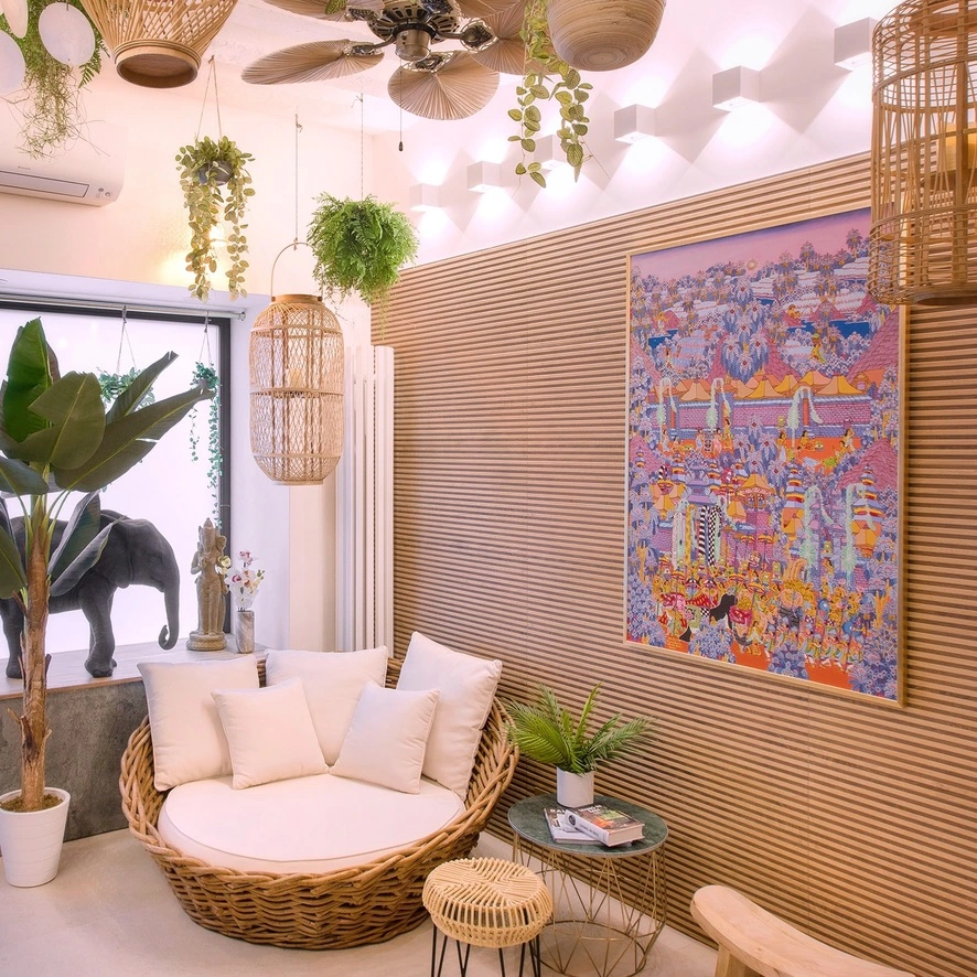 Fauteuil en rotin, tableau balinais et végétation dans le salon du duplex.