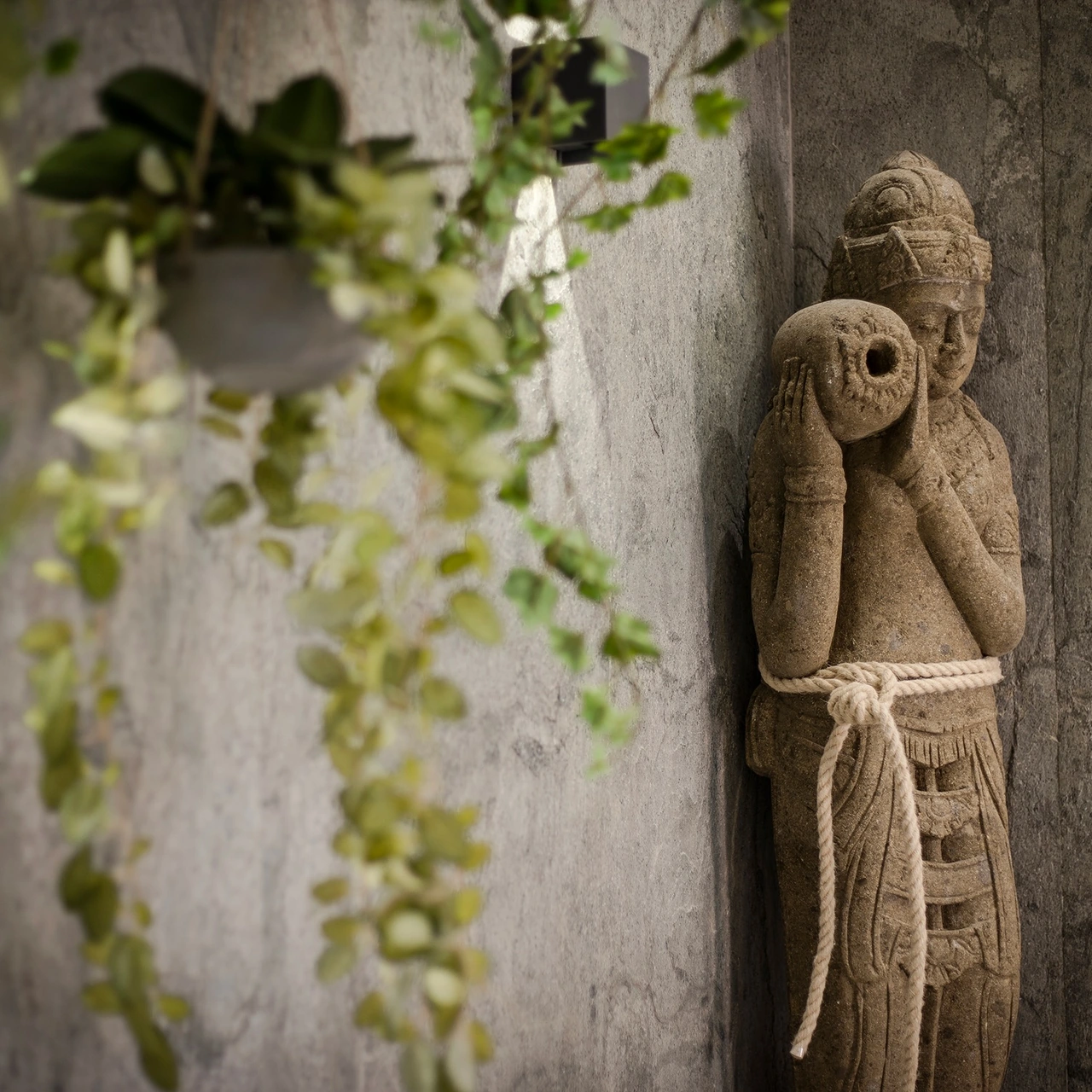 Grande sculpture balinaise contre le mur en pierre naturelle